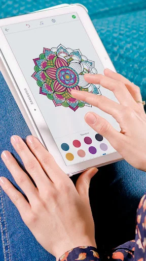 User coloring vibrant mandala design on tablet with Mandala Coloring Pages app, selecting colors from palette at bottom